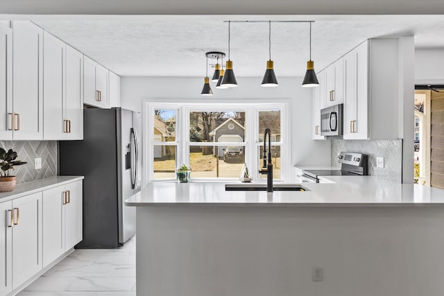 kitchen with decorative light fixtures, appliances with stainless steel finishes, white cabinets, marble finish floor, and a sink