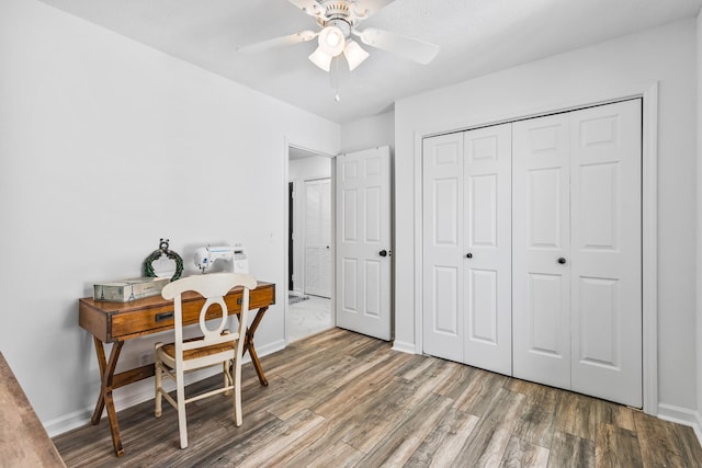 office space featuring baseboards, a ceiling fan, and wood finished floors