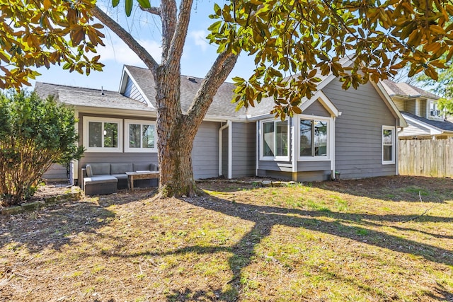 back of property featuring fence, a lawn, and a shingled roof