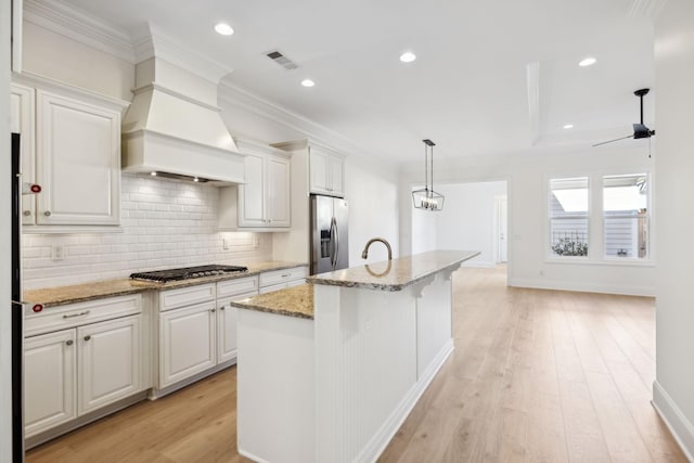 kitchen featuring light wood-type flooring, visible vents, custom range hood, appliances with stainless steel finishes, and crown molding