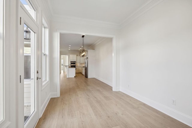 interior space featuring light wood-type flooring, crown molding, and baseboards