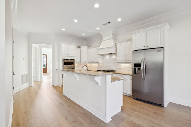 kitchen with visible vents, premium range hood, decorative backsplash, stainless steel appliances, and white cabinetry