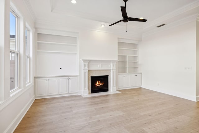 unfurnished living room featuring crown molding, light wood-style flooring, visible vents, and ceiling fan