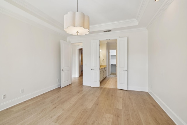 spare room featuring light wood finished floors, visible vents, a raised ceiling, and baseboards