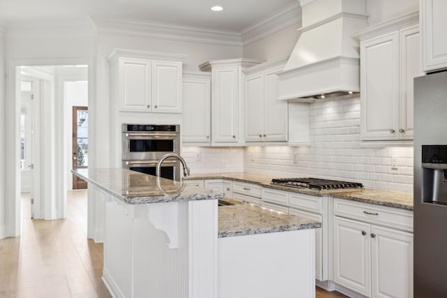 kitchen featuring ornamental molding, decorative backsplash, stainless steel appliances, custom exhaust hood, and white cabinetry