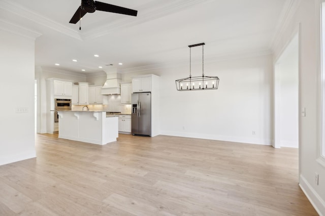 unfurnished living room with ceiling fan with notable chandelier, light wood-type flooring, and crown molding