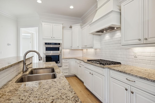 kitchen featuring premium range hood, stainless steel appliances, ornamental molding, and a sink