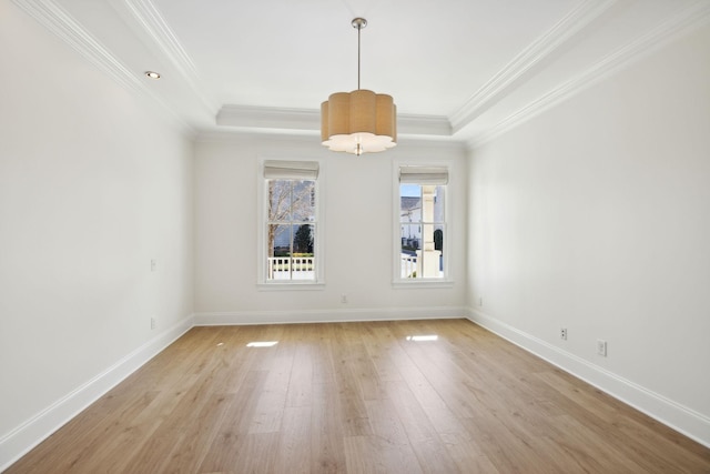 empty room with crown molding, baseboards, light wood-style floors, and a tray ceiling