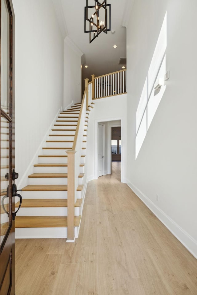 foyer with baseboards, a chandelier, stairs, recessed lighting, and wood finished floors