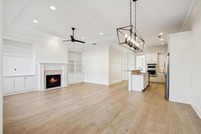 kitchen featuring a fireplace with flush hearth, ceiling fan with notable chandelier, stainless steel appliances, and open floor plan