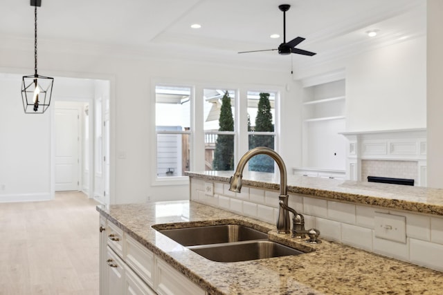 kitchen with ornamental molding, pendant lighting, ceiling fan, and a sink