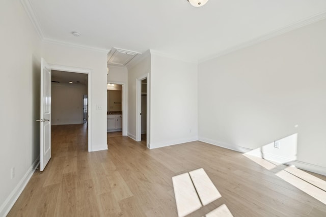 interior space with attic access, light wood-style flooring, crown molding, and baseboards