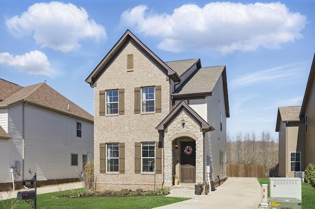 view of front facade with fence, stone siding, and central AC