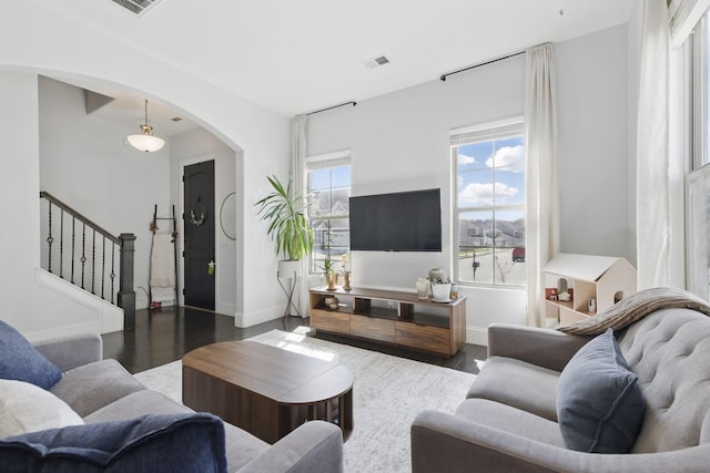 living area with a wealth of natural light, arched walkways, and wood finished floors