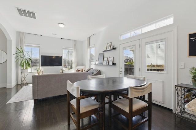 dining room featuring visible vents, baseboards, dark wood-type flooring, and arched walkways