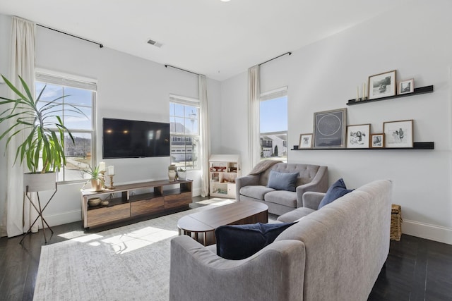 living room with plenty of natural light, baseboards, visible vents, and wood finished floors