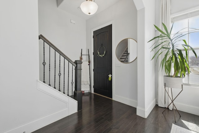 entrance foyer featuring stairs, wood finished floors, baseboards, and arched walkways