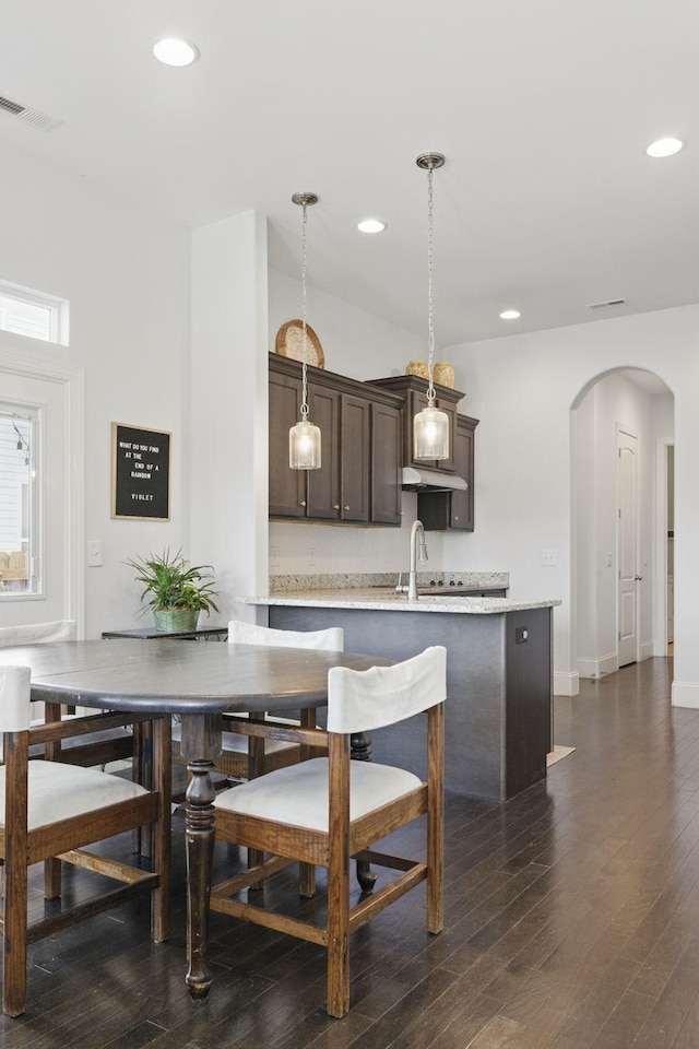 dining room featuring recessed lighting, arched walkways, dark wood-style flooring, and baseboards