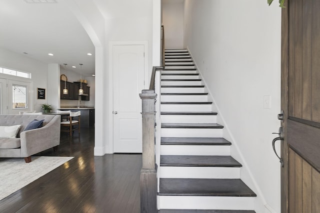 staircase with visible vents, recessed lighting, wood-type flooring, arched walkways, and baseboards