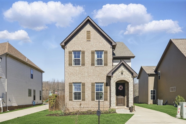 view of front facade featuring brick siding, central AC, and a front yard