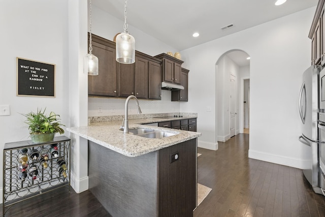 kitchen featuring visible vents, dark wood finished floors, arched walkways, a sink, and dark brown cabinets