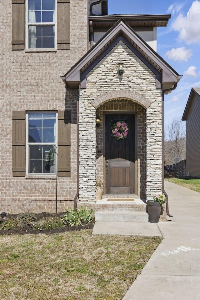 view of exterior entry featuring brick siding and stone siding