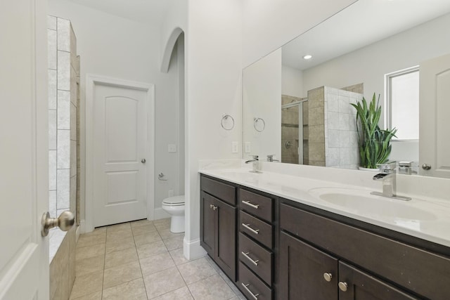 full bath with a sink, double vanity, a shower stall, and tile patterned flooring