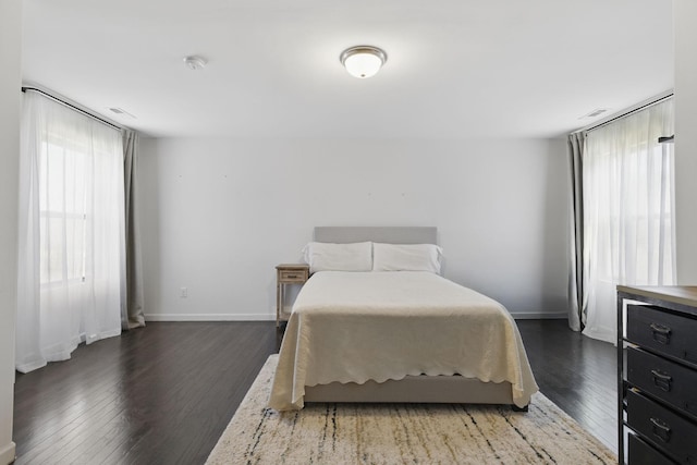 bedroom with multiple windows, baseboards, and wood finished floors