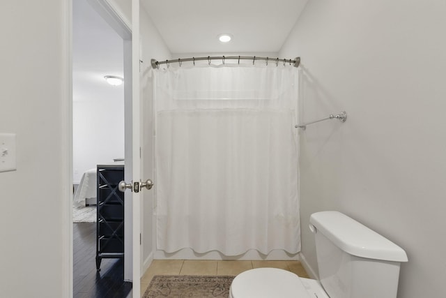 full bath featuring tile patterned floors, shower / bath combo with shower curtain, and toilet