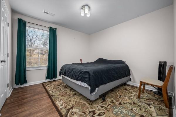 bedroom featuring wood finished floors, visible vents, and baseboards