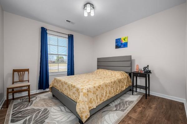 bedroom featuring visible vents, baseboards, and wood finished floors