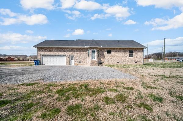 ranch-style house featuring gravel driveway and an attached garage