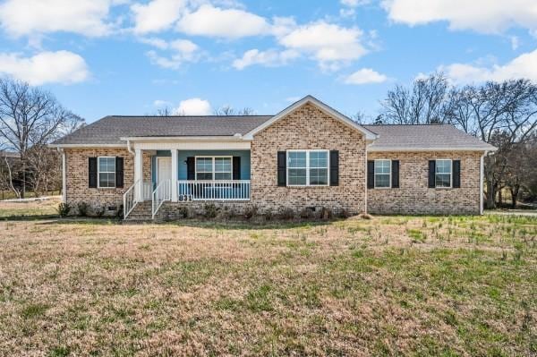 ranch-style home featuring brick siding, covered porch, and a front lawn