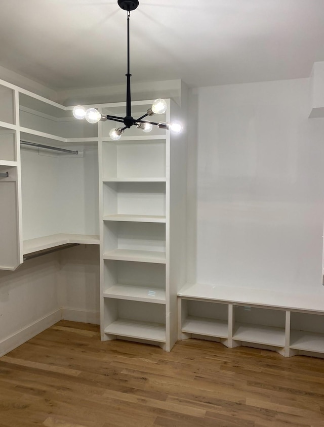 walk in closet featuring wood finished floors and a chandelier