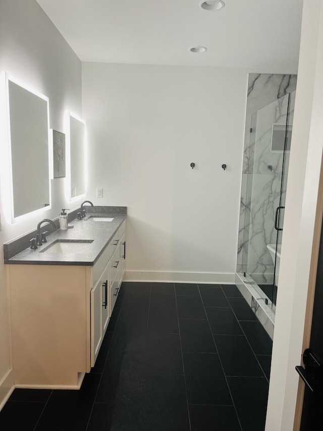 full bathroom featuring double vanity, baseboards, a marble finish shower, and a sink