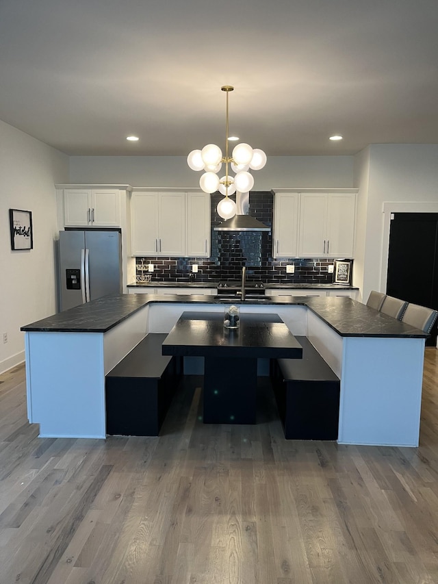 kitchen featuring tasteful backsplash, dark countertops, wood finished floors, white cabinetry, and stainless steel fridge with ice dispenser