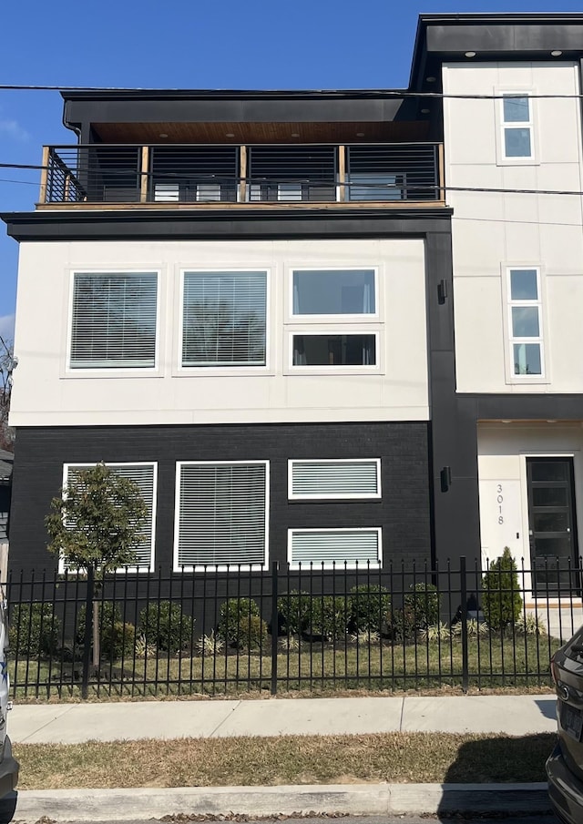 view of front facade featuring a fenced front yard and a balcony