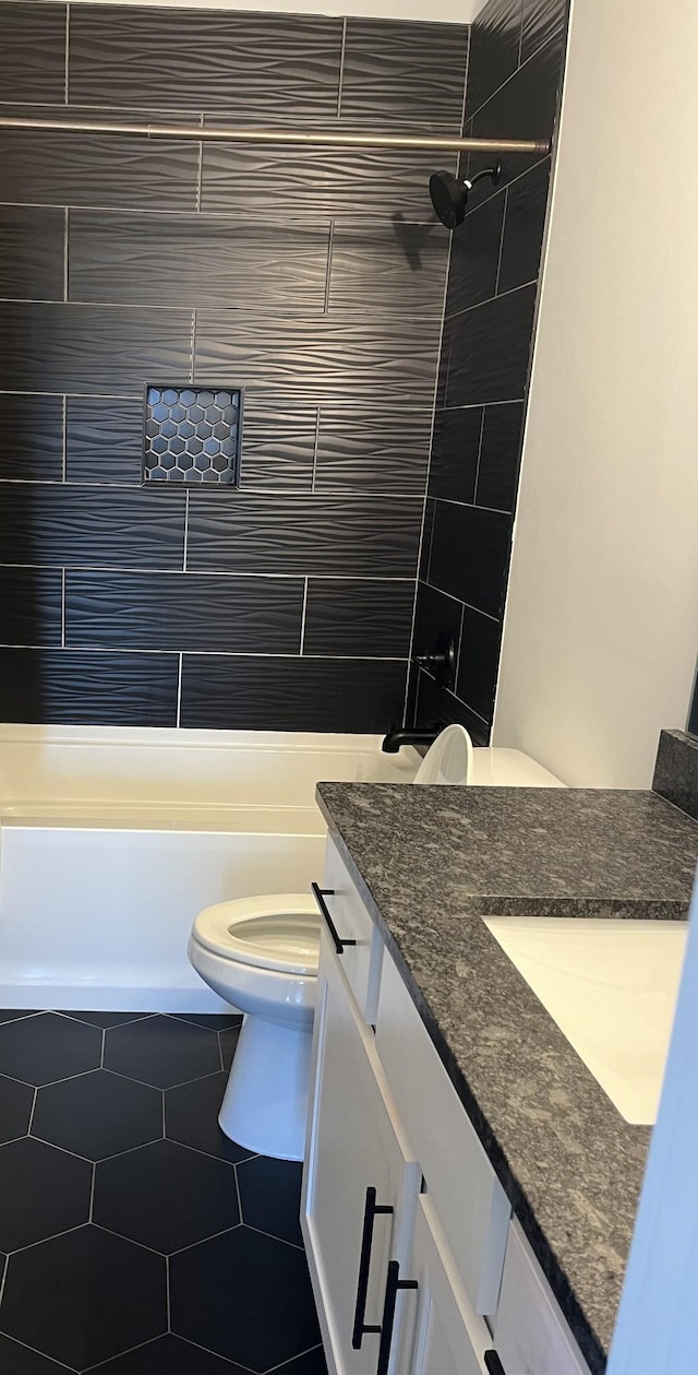 full bath featuring tiled shower / bath combo, toilet, vanity, and tile patterned flooring