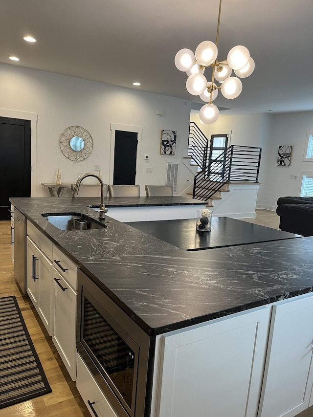 kitchen with a notable chandelier, a sink, a spacious island, white cabinets, and built in microwave