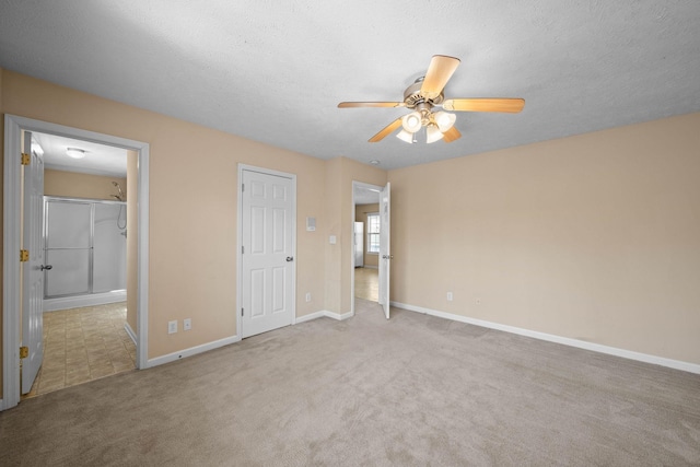 unfurnished bedroom with ensuite bath, carpet flooring, a textured ceiling, and baseboards