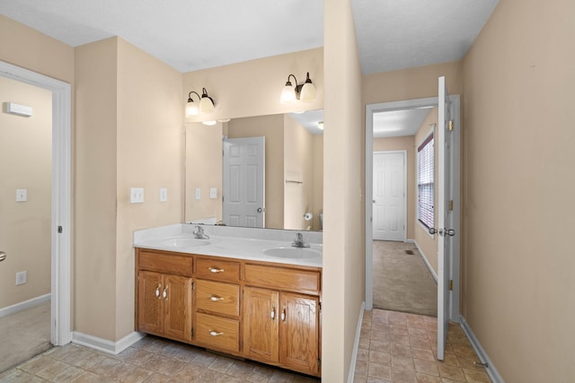 full bath with double vanity, baseboards, and a sink