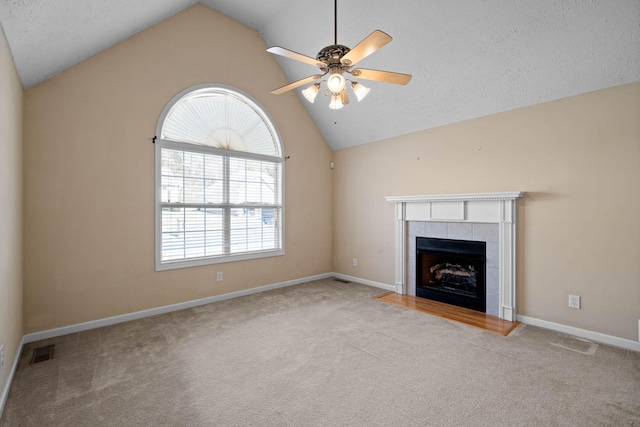 unfurnished living room featuring visible vents, vaulted ceiling, carpet floors, a fireplace, and a ceiling fan