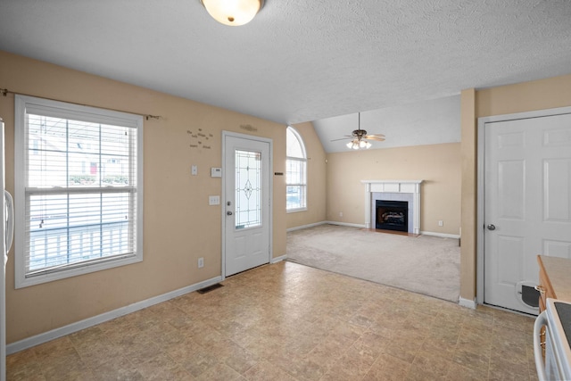 entrance foyer with visible vents, baseboards, a fireplace with flush hearth, lofted ceiling, and a ceiling fan