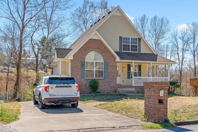 view of front facade featuring brick siding, a porch, a shingled roof, and driveway