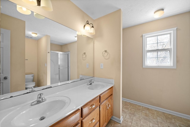 full bath featuring a stall shower, toilet, baseboards, and a sink