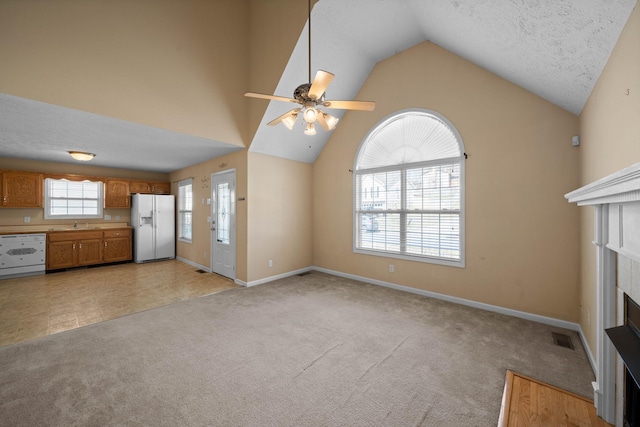 unfurnished living room with visible vents, light carpet, baseboards, and a ceiling fan