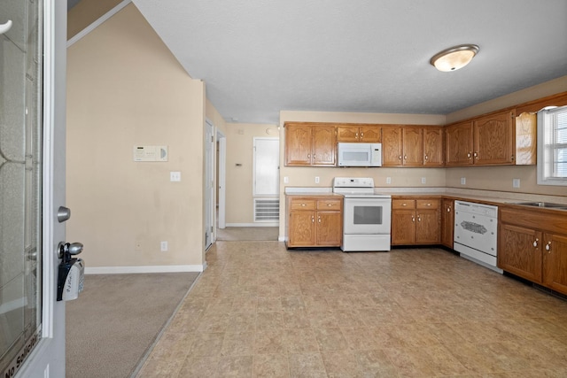 kitchen with white appliances, baseboards, brown cabinets, and light countertops