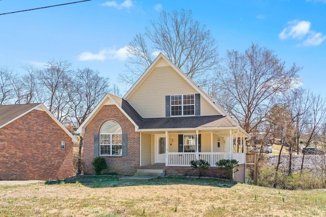 view of front of property featuring brick siding, covered porch, a front yard, and a shingled roof