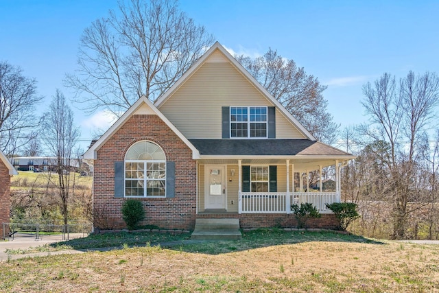 view of front of home featuring brick siding, covered porch, and a front lawn