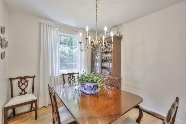 dining space with light wood-style flooring, a notable chandelier, and baseboards